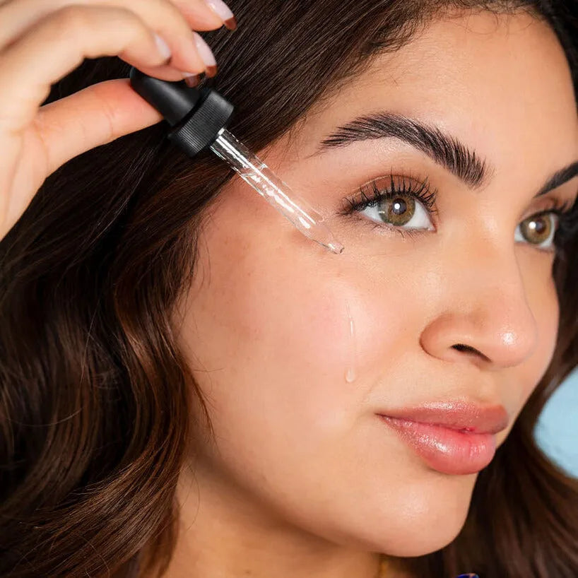Woman applying serum with a dropper to her cheek, highlighting her glowing complexion and smooth skin—a perfect moment of skincare self-care.