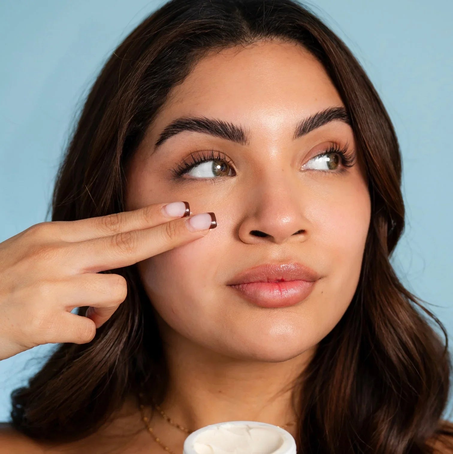 Woman applying Bohemia Skin cream to face, highlighting clean skincare routine