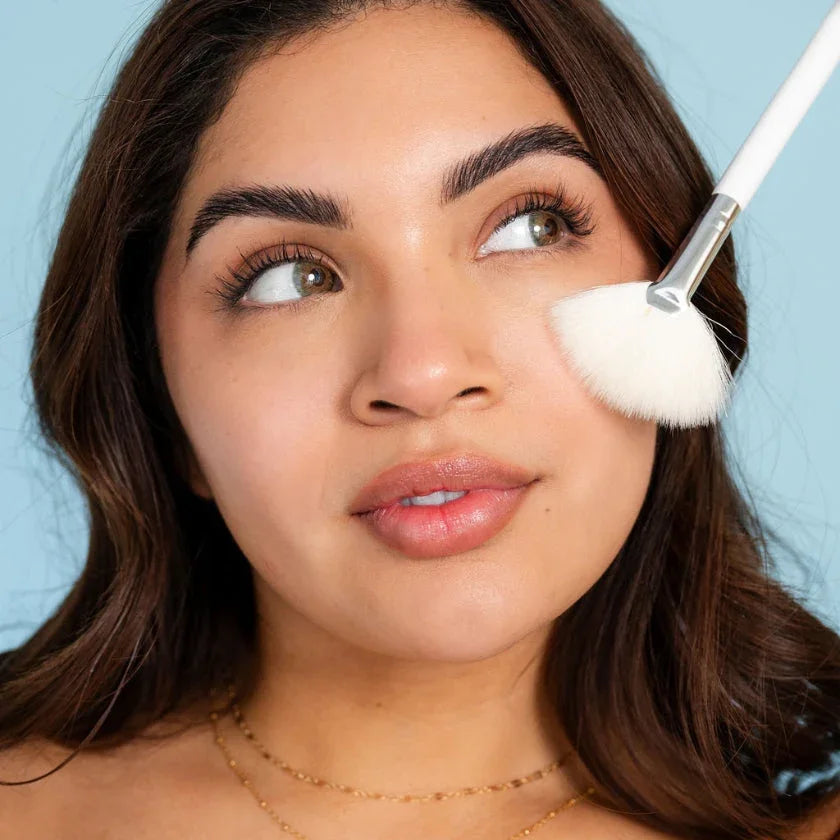 Woman using a Bohemia Skin fan brush on cheek for clean holistic skincare