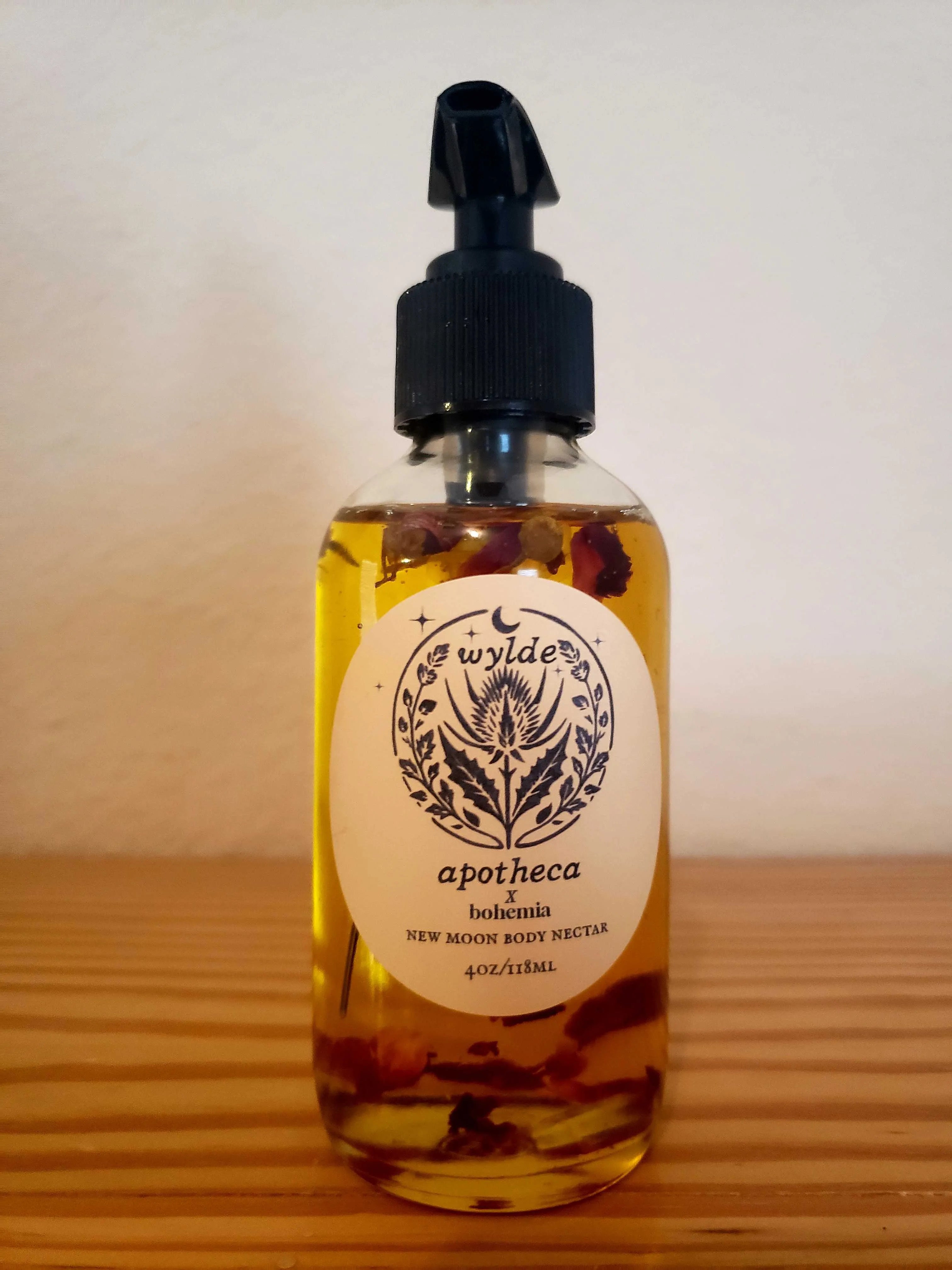 Bohemia Skin New Moon Body Nectar oil bottle with natural botanicals on wood surface.